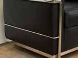 black leather lounge chair with chrome frame and arm rests against a white wall