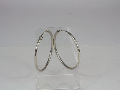 pair of silver hoop earrings on clear acrylic stand