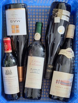 plusieurs bouteilles de vin dans un panier bleu posé sur la table