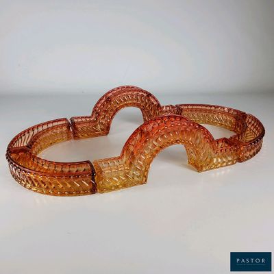 deux bracelets en verre orange posés sur une surface blanche, sur fond blanc