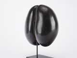 sculpture of a black egg on a black stand on a white background