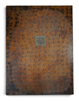 an old book with a brown cover sitting on top of a white surface