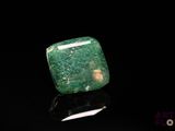 a close up of a green stone on a black surface