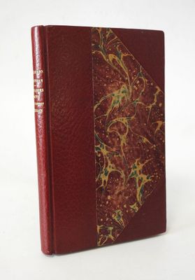an old book with a red cover sitting on top of a white table