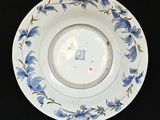 a white plate with blue flowers on it on a stand