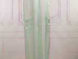 a green dress on a mannequin stand in front of a white wall