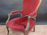 a red chair sitting on top of a carpeted floor next to a wall