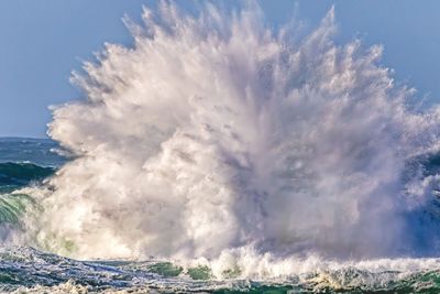 des vagues qui se brisent sur le rivage d'une plage, avec une personne sur une planche de surf au premier plan