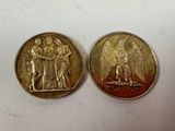 two gold coins with angels on them sitting next to each other