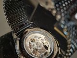 someone is holding a watch with a black strap around it