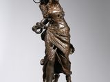 a bronze statue of a woman holding a bird on a pedestal