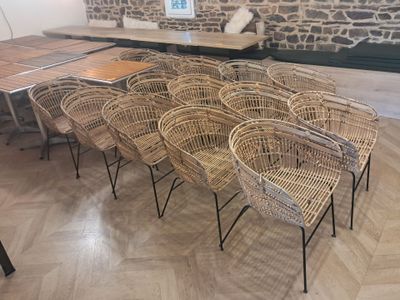 plusieurs chaises en osier et une table dans une pièce aux murs en pierre