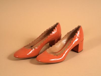 une paire d'escarpins orange à talons festonnés sur une base beige