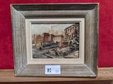 un tableau représentant une scène de rue, encadré et posé sur une étagère