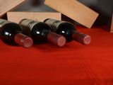 several bottles of wine sitting on a red table cloth next to a wooden box