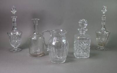 five glass vases and a glass bottle on a table