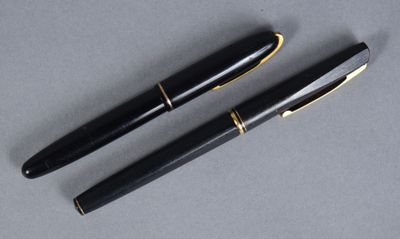 two black pens sitting next to each other on top of a table