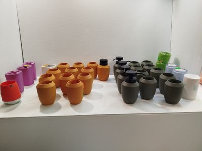 de nombreux vases de différentes couleurs posés sur une étagère blanche