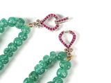 a close up of a pair of green beads with pink stones