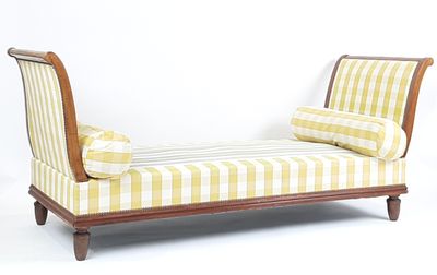 une chaise longue rayée jaune et blanche devant un mur blanc