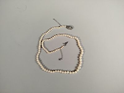 a white pearl necklace with a silver clasp on a white table