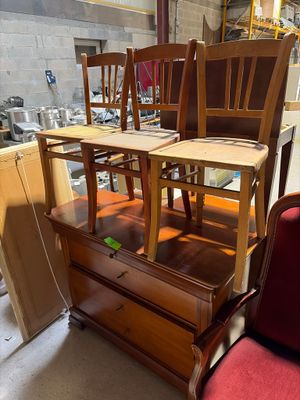 Plusieurs chaises et une table sont empilées les unes sur les autres dans un entrepôt
