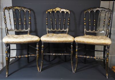 trois chaises aux finitions dorées sur fond noir