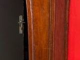 une grande horloge de parquet en bois devant un mur rouge
