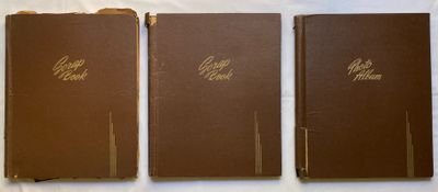 trois livres marron sont alignés sur une surface blanche