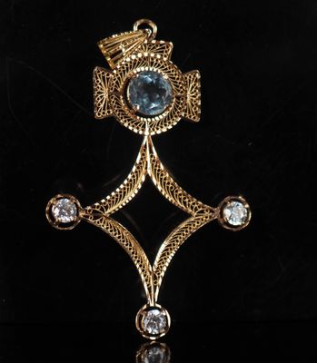 a close up of a gold broochle with a blue stone