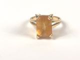 une image représentant une bague ornée d'une pierre jaune sur un fond blanc