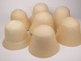 six chapeaux de paille sont alignés sur une surface blanche