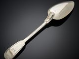 une cuillère ancienne en argent posée sur une surface noire, avec un fond noir