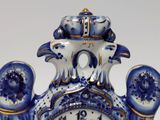 a blue and white vase with a clock on it