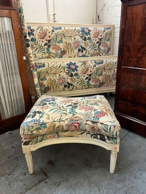 une chaise dont l'assise est recouverte d'un tissu à motifs floraux, placée à côté d'une commode