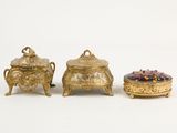 three pieces of gold and glass are sitting on a white surface