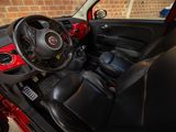 the interior of a small red car with a steering wheel and dashboard
