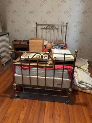 a bed that is in a room with a lot of stuff on the floor
