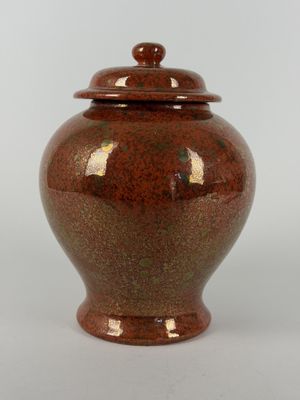 an image of a red vase with a lid sitting on a white surface