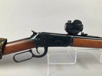 a rifle with a wooden barrel and metal sights on a clear stand
