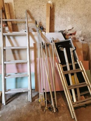 une échelle appuyée contre un mur, à côté d'un tas de matériaux de construction