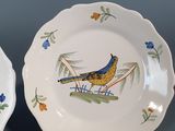 two plates with birds painted on them sitting on a table