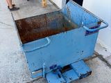une brouette bleue sur le trottoir, à côté d'une machine jaune
