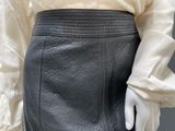 a close up of a woman ' s leather skirt with a white shirt