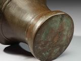 a close up of a bronze vase on a white surface