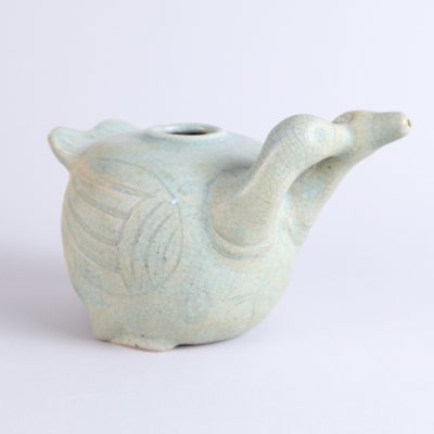 a small teapot with a handle on a white surface