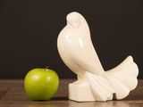 a white bird figurine next to an apple on a table