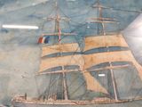 a painting of a ship on display in a glass case
