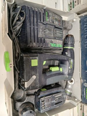 une perceuse à fil noir et vert et deux autres outils dans une boîte