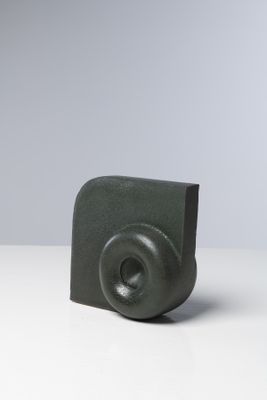 une photo représentant une sculpture noire posée sur une table blanche